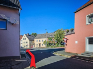 Hauptstraße hinter zwei rötlichen Häusern