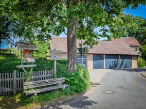 Wegweiser neben Baum und Bank