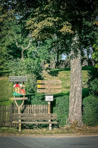 Wegweiser neben Baum und Bank