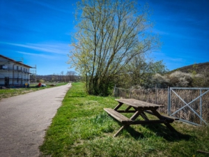 An Holzbank-Sitzgruppe vor Weiher vorbei